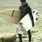 Justin Trudeau on a beach with surfboards.